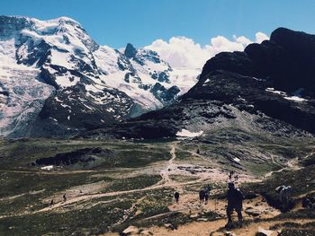 View of hikers with snowcapped mountain range in background