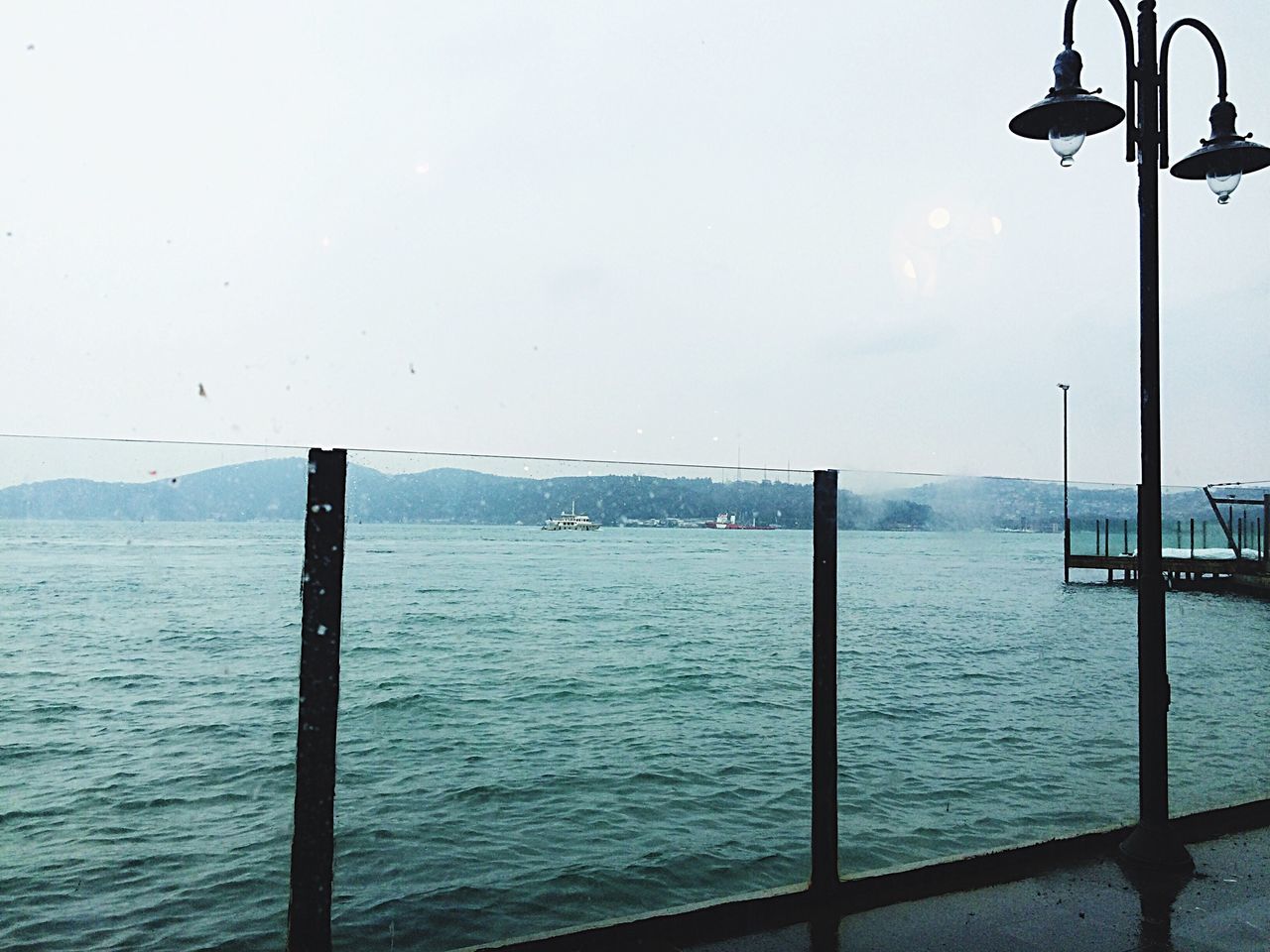 water, sea, street light, sky, tranquility, tranquil scene, pier, scenics, beauty in nature, nature, pole, waterfront, horizon over water, rippled, bird, idyllic, lighting equipment, reflection, outdoors, wooden post