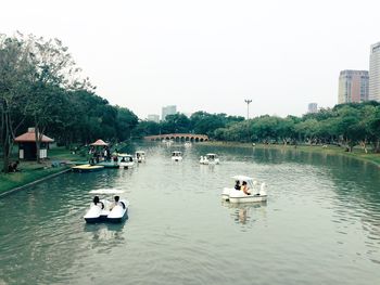 Boats in water against sky in city