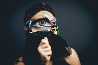 Close-up of woman holding camera against black background