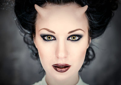 Digital composite image of horned young woman with make-up