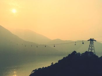 Silhouette mountain by lake against sky during sunset