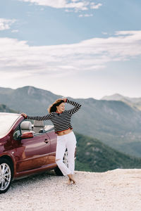 Woman with umbrella walking on mountain against sky