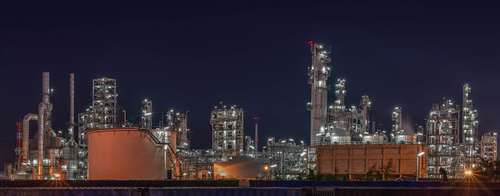 Illuminated factory against sky at night