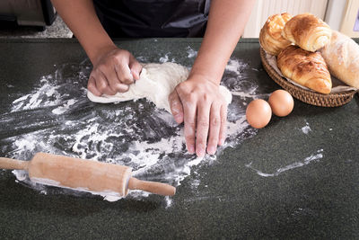 Midsection of person kneading dough in kitchen