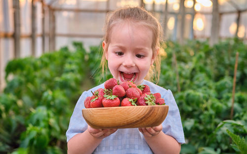 Portrait of cute girl holding strawberries