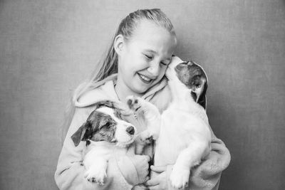 Caucasian beautiful girl with long hair holds two cute jack russell puppies in her arms