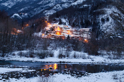 View of illuminated buildings on snow covered land