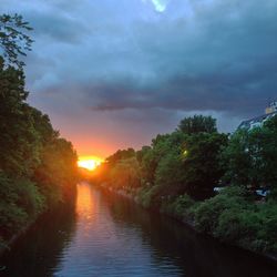 River amidst trees against sky during sunset