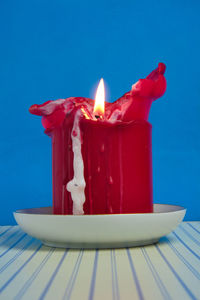 Close-up of lit candles on table against blue background