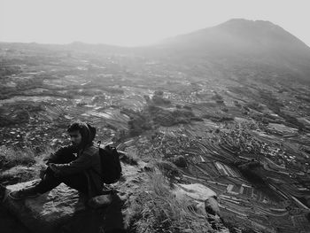 Man sitting on rock against mountain