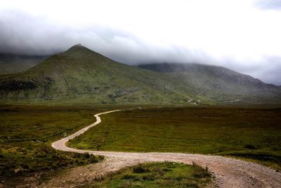 Road leading towards mountains against sky