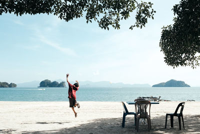 Rear view of boy jumping at beach