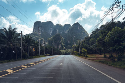 Road by trees against sky