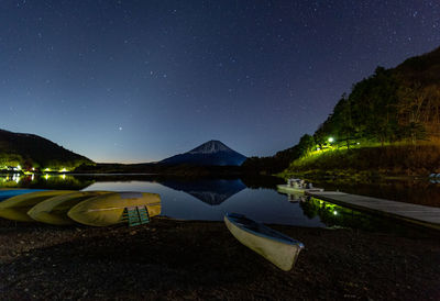 Scenic view of lake by mountains fuji against sky at night