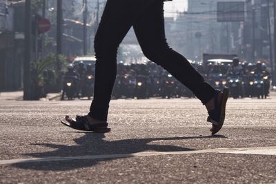 Low section of woman walking on street in city