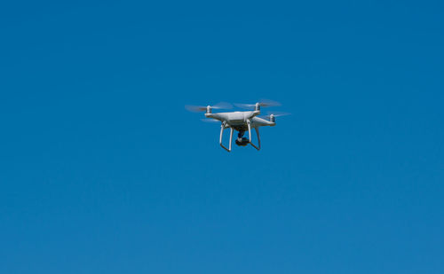 Low angle view of airplane flying against clear blue sky
