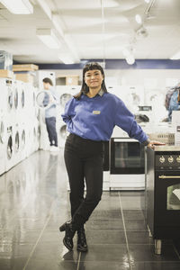 Portrait of smiling saleswoman standing in electronics store