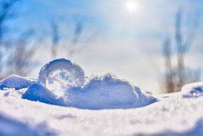 Close-up of snow covered land against bright sun