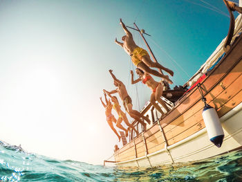 People jumping in sea against sky