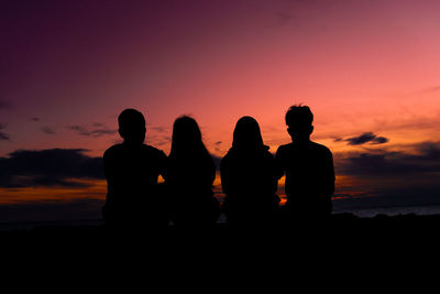 Silhouette people looking at sea against sky during sunset