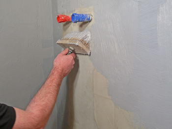 Midsection of man working against wall at home