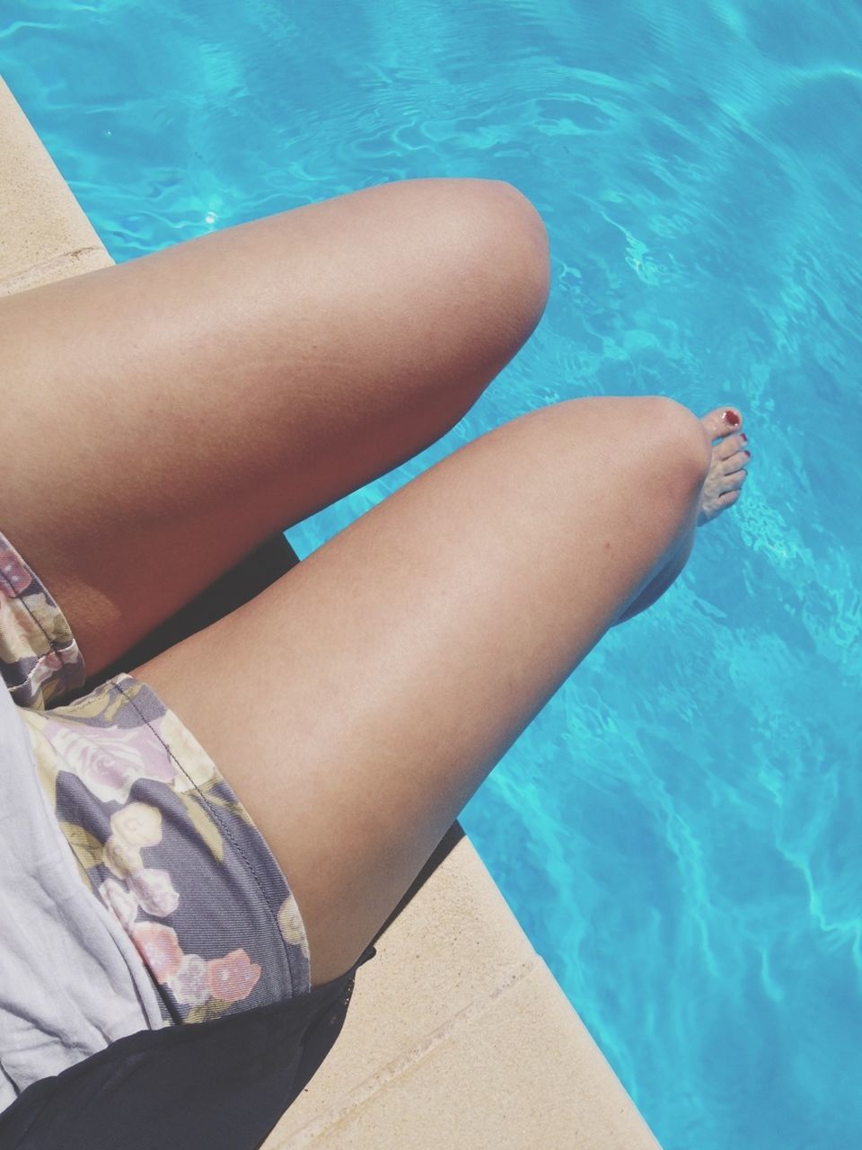 person, low section, swimming pool, lifestyles, water, blue, leisure activity, high angle view, barefoot, human foot, personal perspective, relaxation, sunlight, part of, turquoise colored, sitting