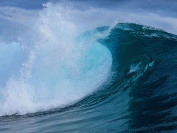 Waves splashing in sea against blue sky