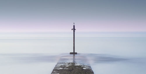 Wooden post on pier over sea against sky