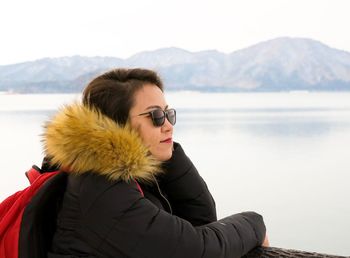 Portrait of woman by lake against sky during winter