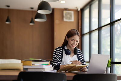 Portrait of young woman using laptop at office