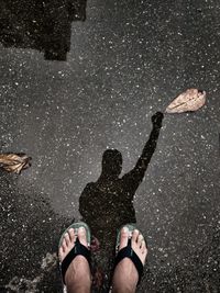 Low section of man standing on wet sand at beach