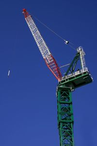 Low angle view of crane against clear blue sky