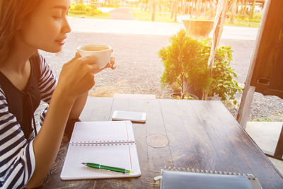 Midsection of woman holding coffee while sitting on table