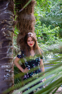 Portrait of young woman against tree trunk