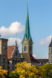 The tower of fraumuenster church in zurich in autumn, with multi colored trees in the foreground