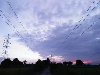 Low angle view of electricity pylon against sky at sunset