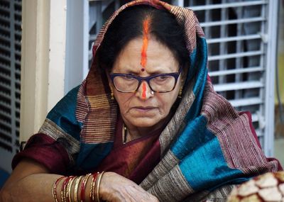 Close-up of woman wearing sindoor and sari at home