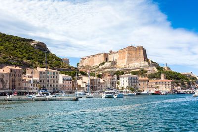 Sailboats in sea against buildings in city