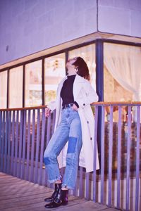 Full length of fashionable woman standing by railing