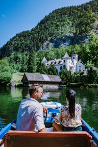 People sitting by lake against trees