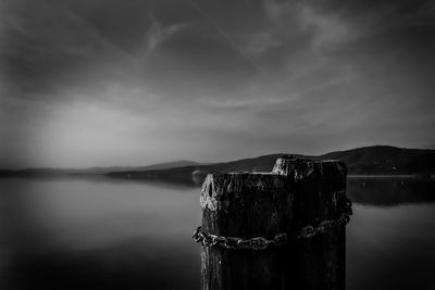 Wooden post in sea against sky