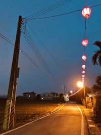 Illuminated street lights against sky at night