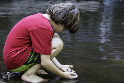 Boy crouching in lake