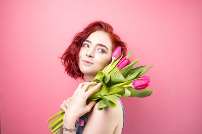 Portrait of smiling young woman against wall