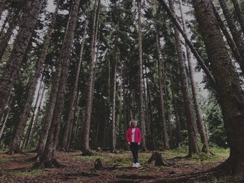 Woman standing by trees in forest