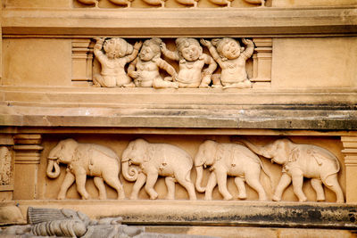 Stone carving of men and elephants on the exterior of a buddhist temple in colombo, sri lanka.