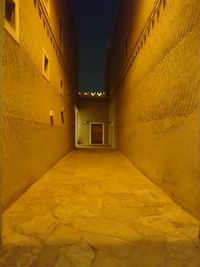 Empty alley amidst buildings at night