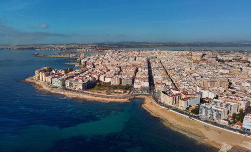 High angle view of city by sea against sky