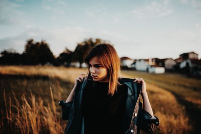 Beautiful woman standing on field against sky during sunset